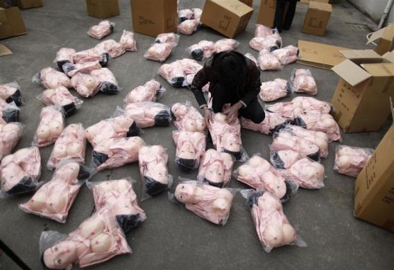 A worker checks an inflatable sex doll as he packs dolls to transfer at Ningbo Yamei plastic toy factory