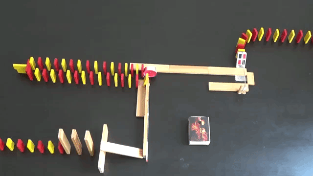 Dominoes Toppling Over Through a Fire and Explosion Fueled Rube Goldberg Track