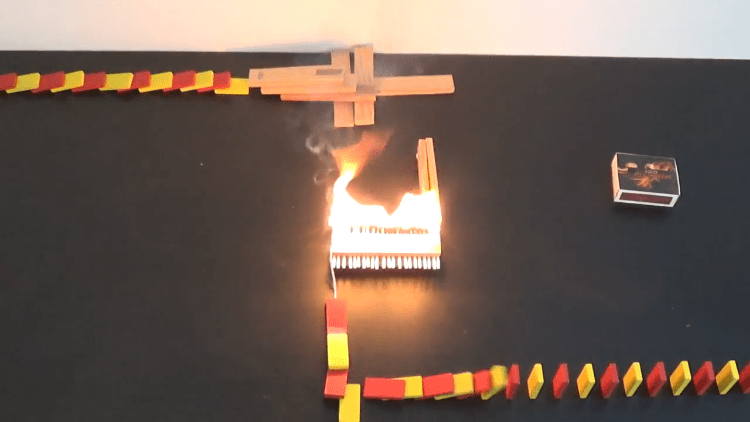Dominoes Toppling Over Through a Fire and Explosion Fueled Rube Goldberg Track