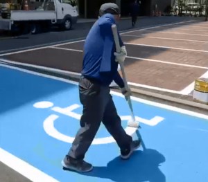 A Man Effortlessly Paints the Pictogram of a Person in a Wheelchair for a Handicap Parking Space