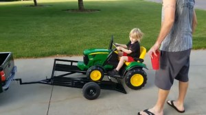 A Little Boy Drives His Toy John Deere Tractor Onto a Custom Made Mini Trailer