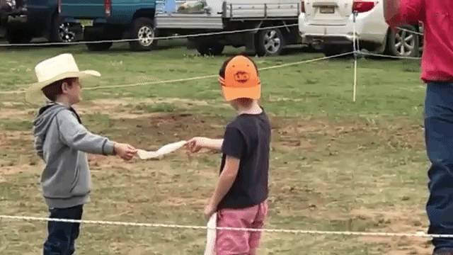 Two Brave Kids Hold a Strip of Paper While a Man Cuts It in Half With a Whip