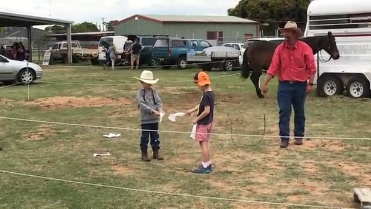 Two Brave Kids Hold a Strip of Paper While a Man Cuts It in Half With a Whip