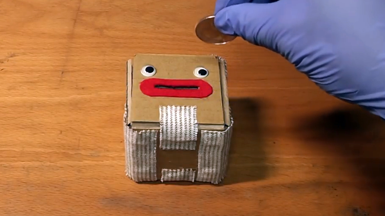 A Cute Cardboard Coin Box That Blasts Open When Money Is Put Into Its Mouth