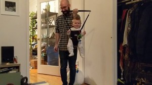 A Father Does Curls Using His Excited Baby Son Who Is in a Jolly Jumper Exerciser
