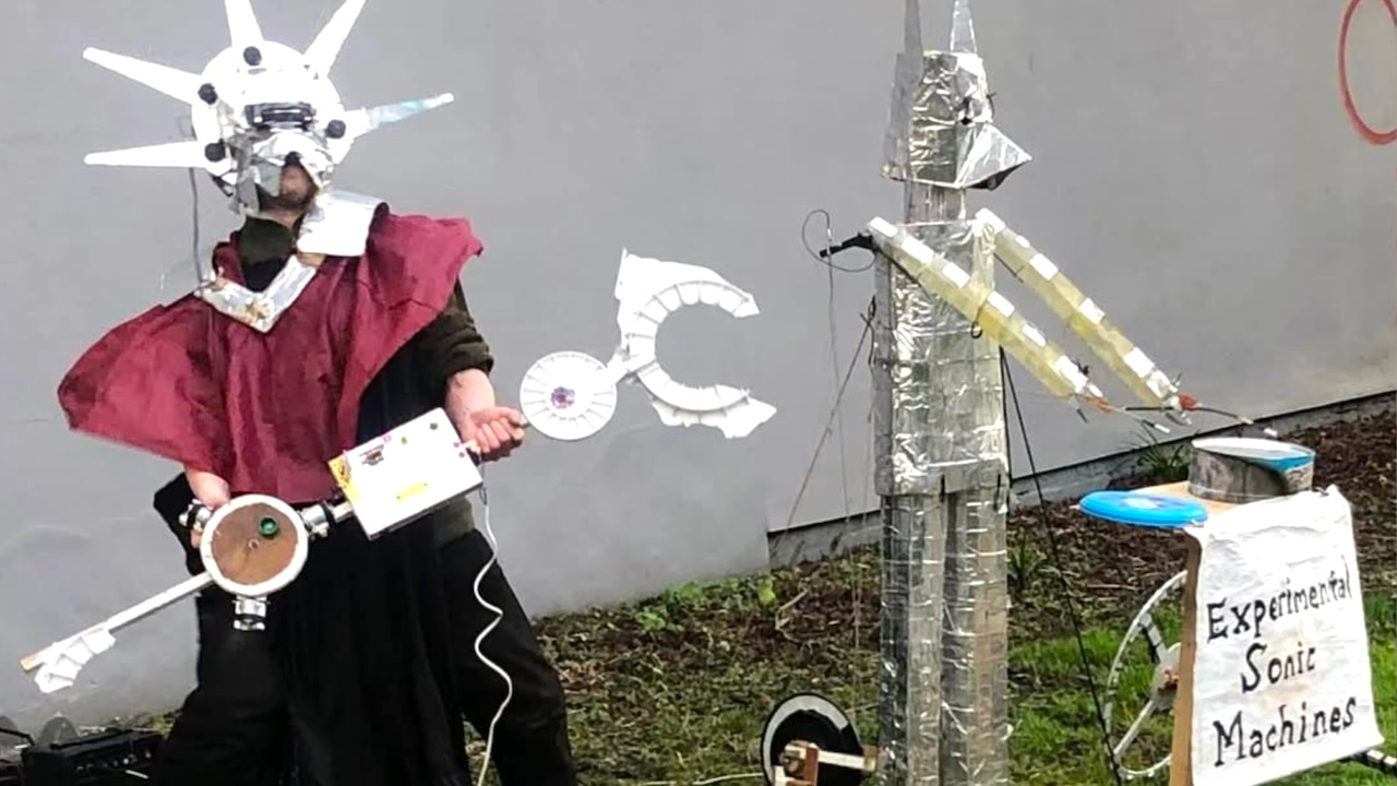 Masked Musician Plays Fantastical Handmade Instruments Alongside a Robotic Drummer Named Ernie