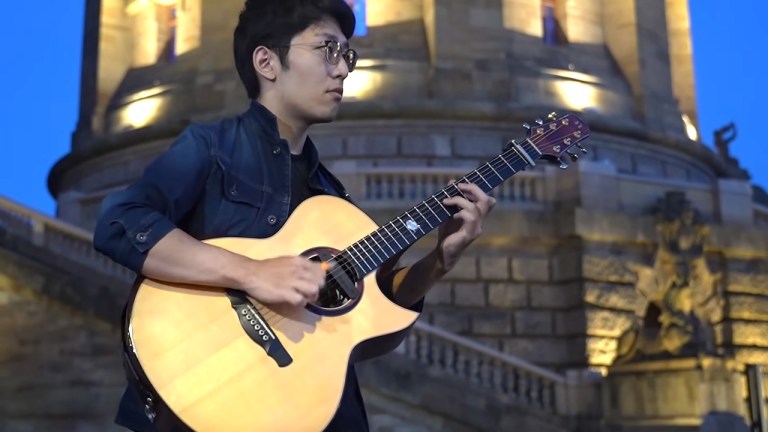 Kent Nishimura playing an acoustic guitar during his fingerstyle performance of Michael Jackson's "Thriller"